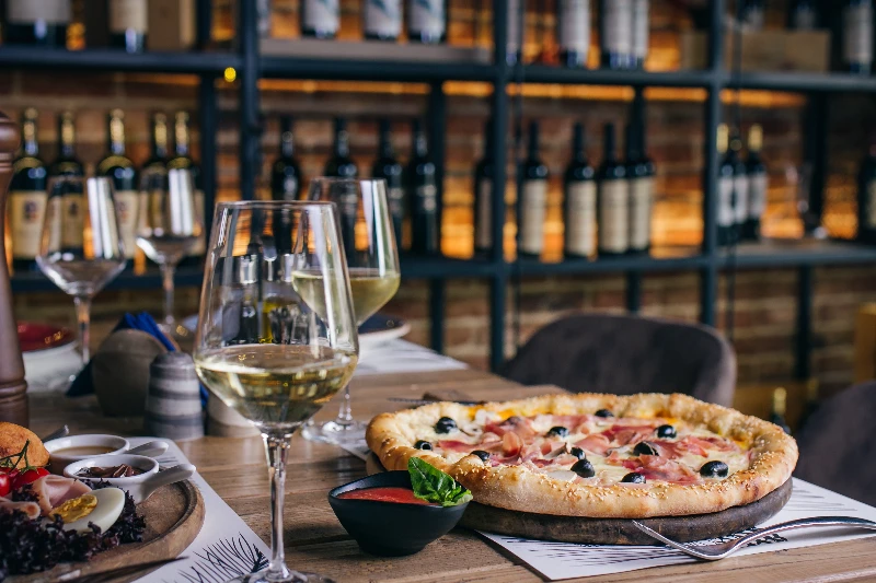 Blog 6 Pizza with prosciutto and olives with wine in restaurant