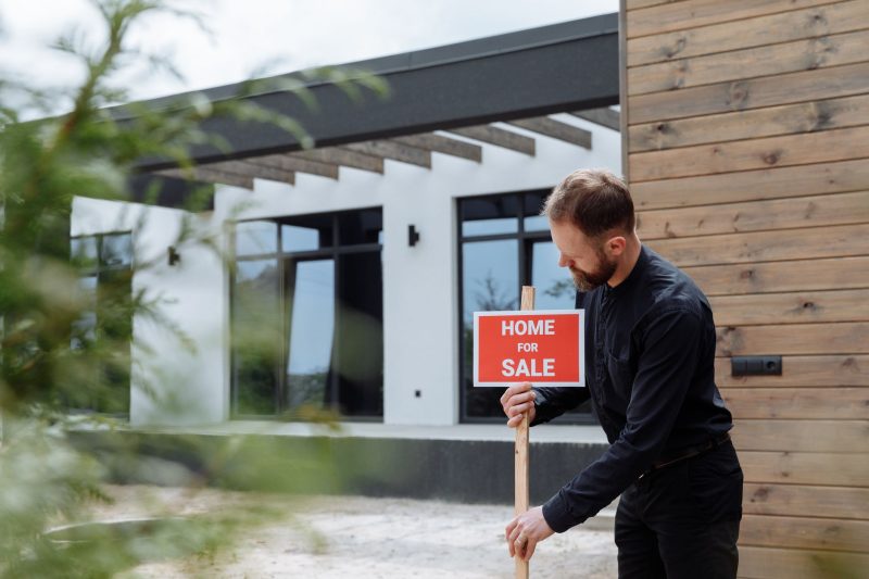 Home 13 Man placing a home for sale sign outside a modern house for 1785862952